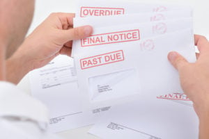 Person holding window envelopes with past due stamps